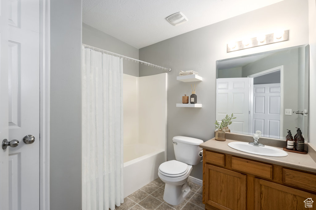 Full bathroom featuring vanity, shower / bath combination with curtain, toilet, and tile patterned floors