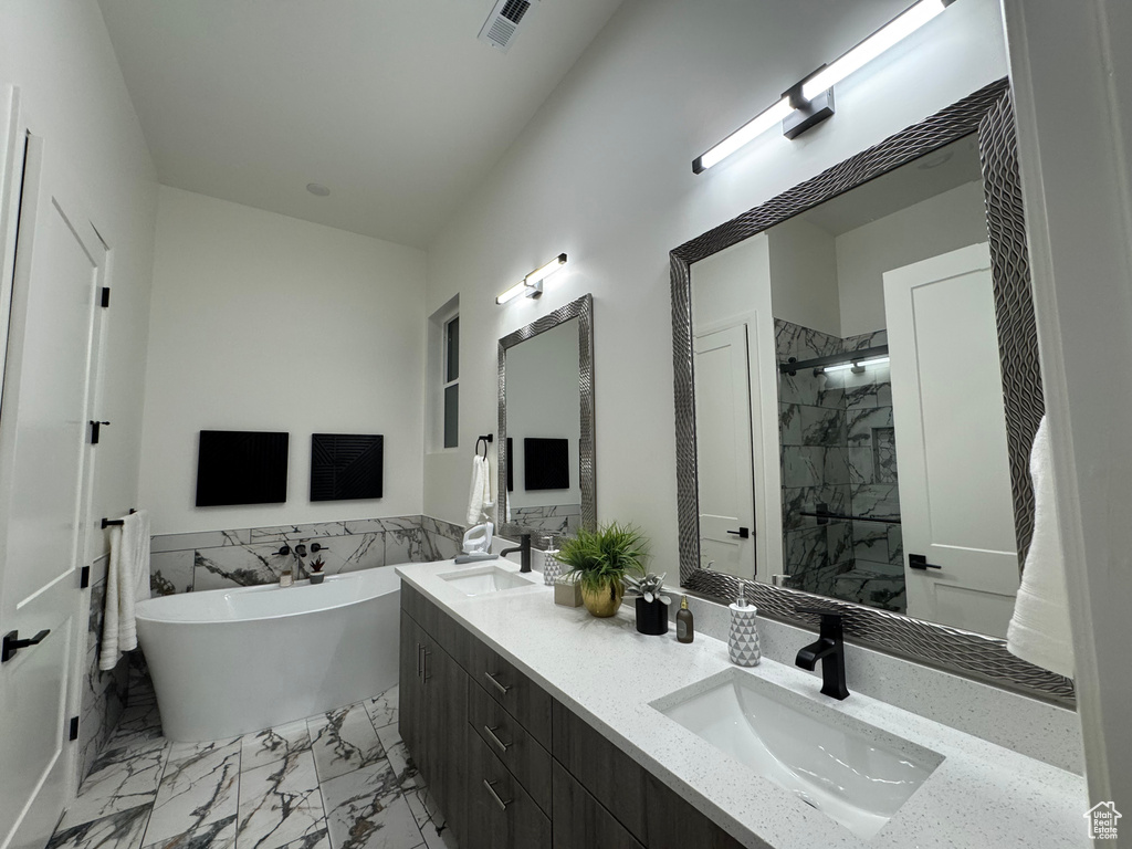 Bathroom featuring vanity and separate shower and tub