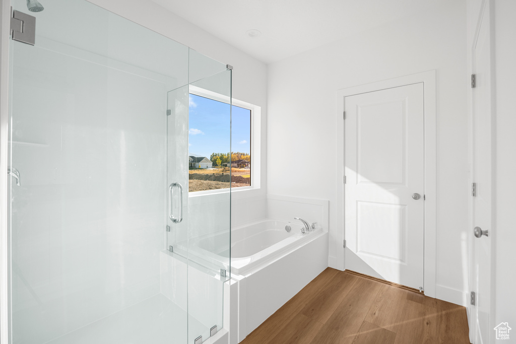 Bathroom with independent shower and bath and wood-type flooring