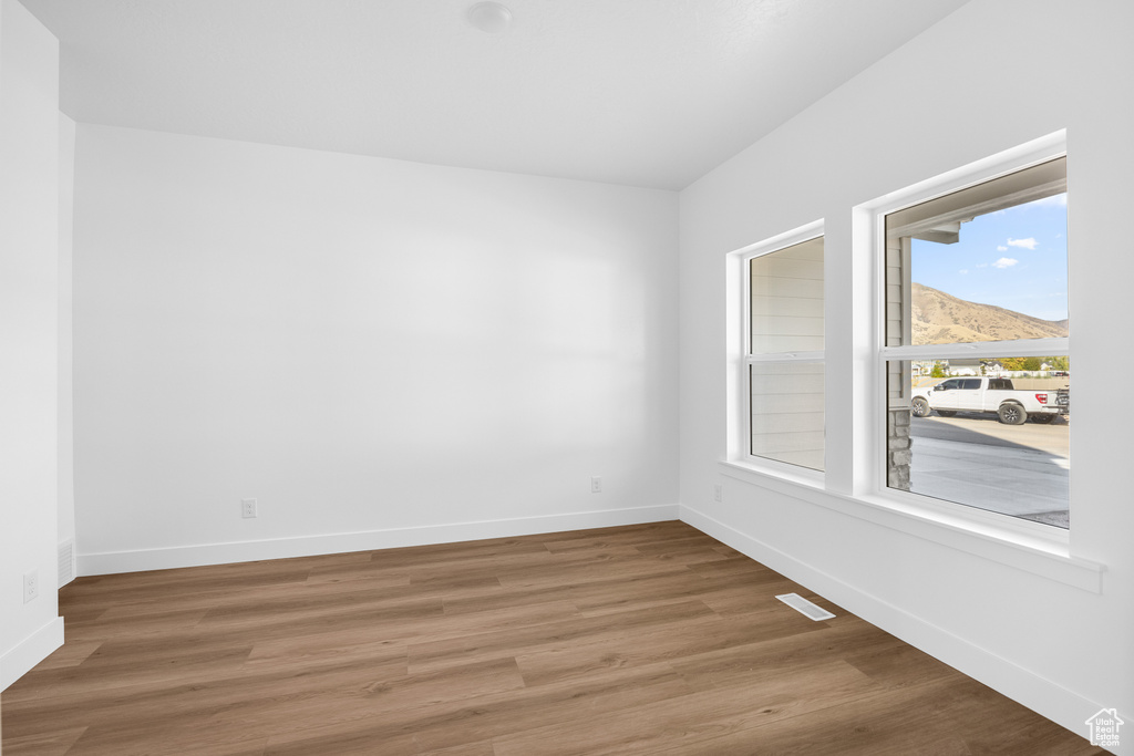 Empty room featuring a mountain view and hardwood / wood-style flooring