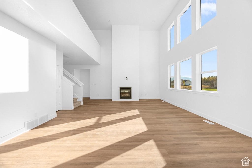 Unfurnished living room with a high ceiling and light wood-type flooring