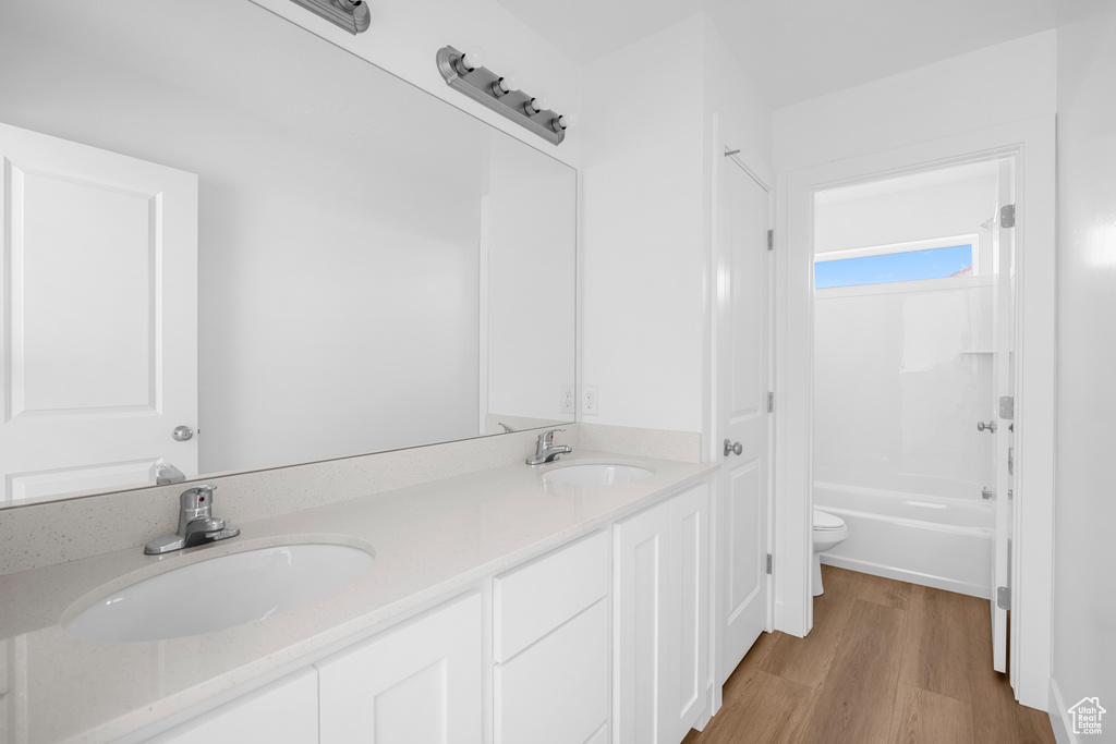 Full bathroom featuring vanity, toilet, wood-type flooring, and  shower combination