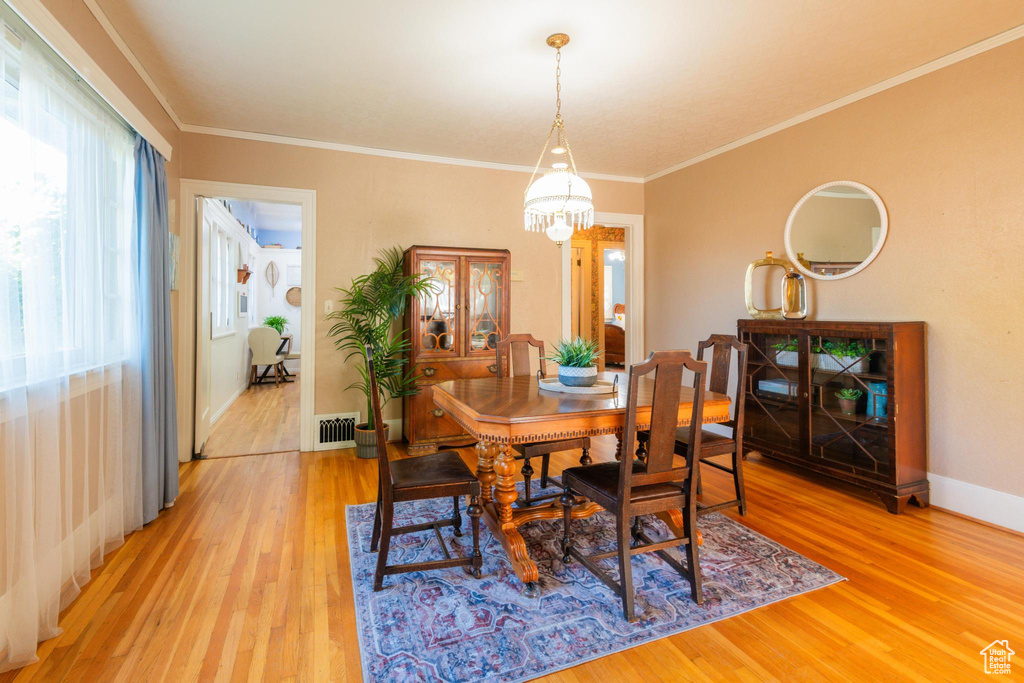 Dining room featuring ornamental molding, a chandelier, and light wood-type flooring