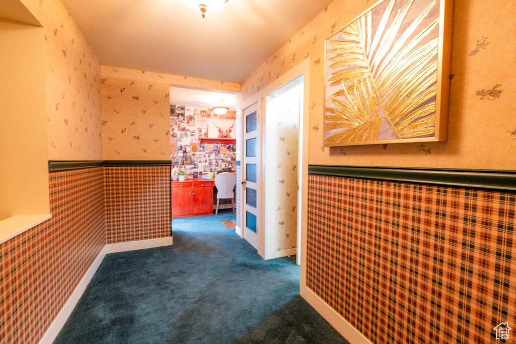 Hallway featuring dark colored carpet