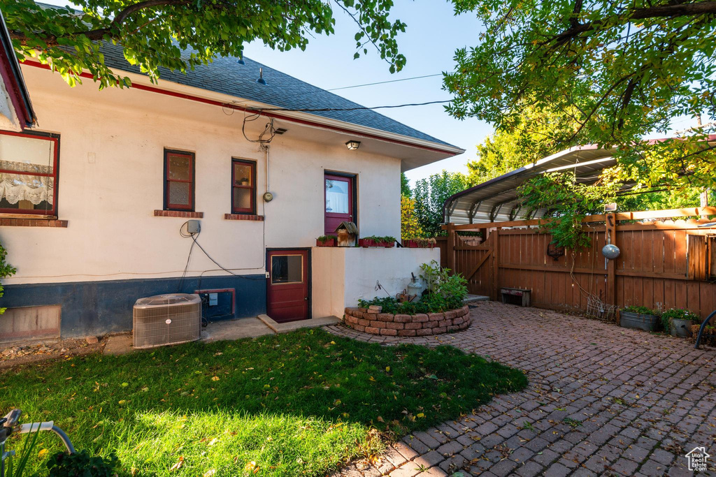 Back of house featuring a yard, central AC unit, and a carport