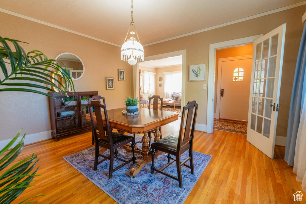 Dining space with light hardwood / wood-style floors and crown molding