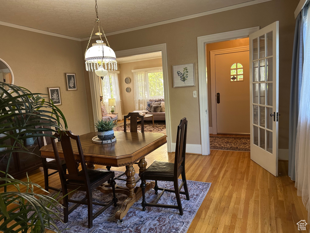 Dining space with crown molding, a textured ceiling, and light hardwood / wood-style flooring