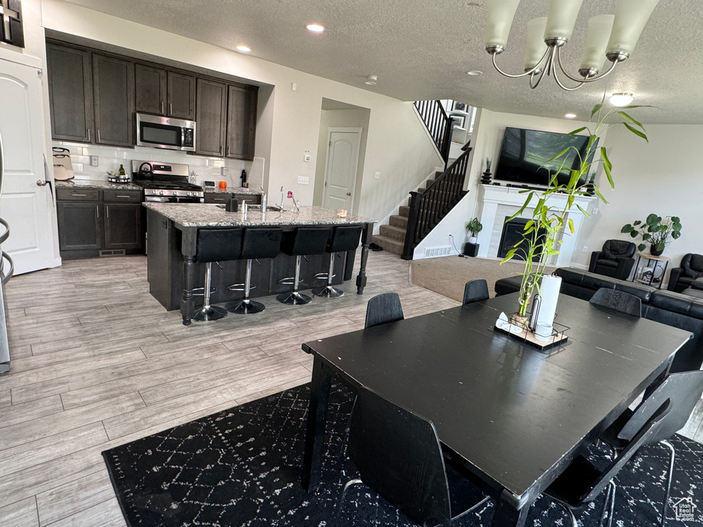 Dining area featuring sink, a chandelier, a textured ceiling, and light wood-type flooring
