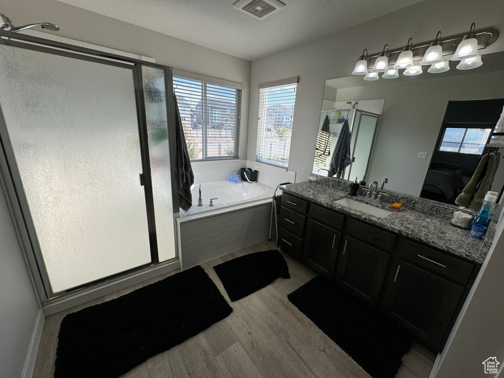 Bathroom with vanity, a textured ceiling, shower with separate bathtub, and hardwood / wood-style floors