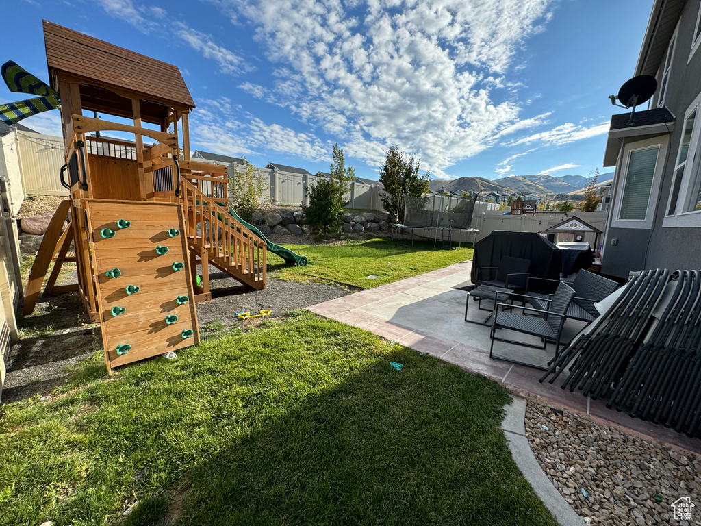 View of yard featuring a patio, a mountain view, a trampoline, and a playground