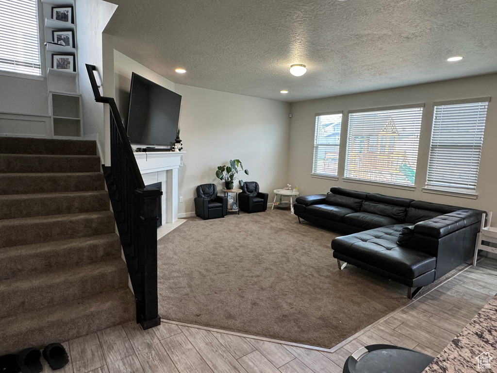 Living room with a tile fireplace, a textured ceiling, and light hardwood / wood-style floors