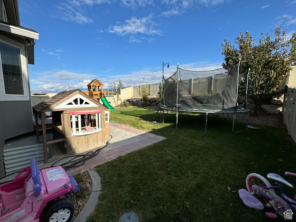 View of yard featuring a patio, a playground, and a trampoline
