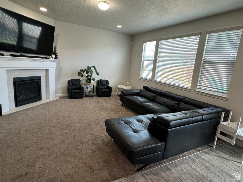 Carpeted living room featuring a textured ceiling and a tile fireplace