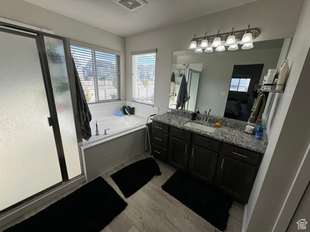 Bathroom with vanity, a textured ceiling, plus walk in shower, and wood-type flooring