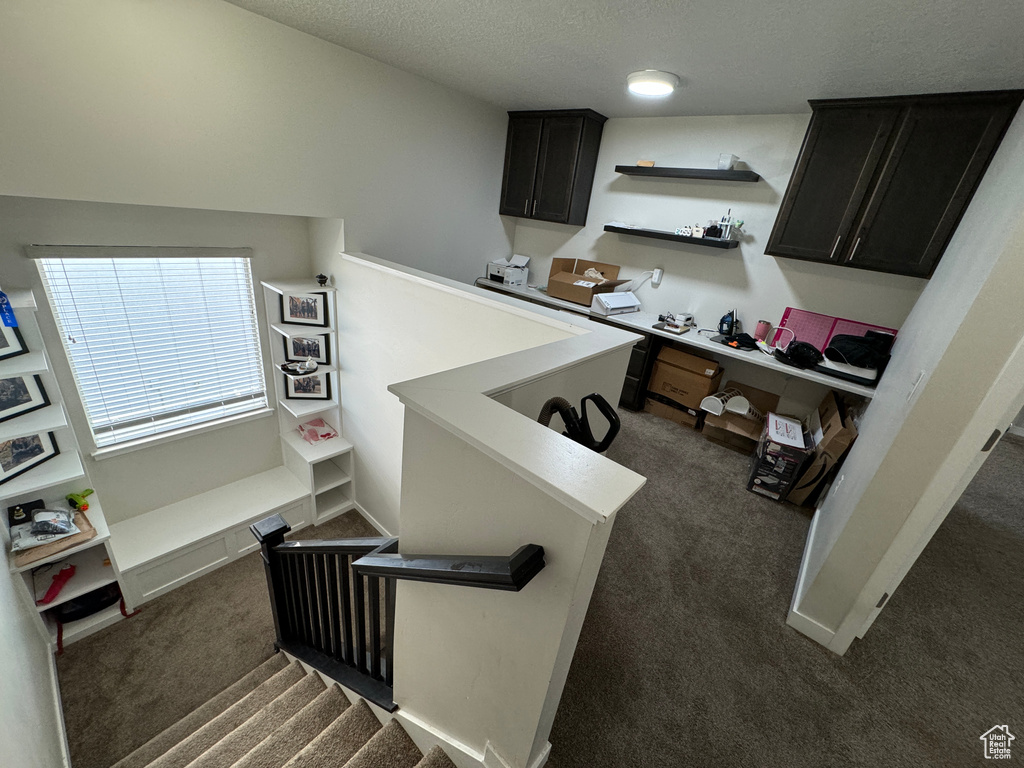 Interior space with lofted ceiling, a textured ceiling, and dark carpet