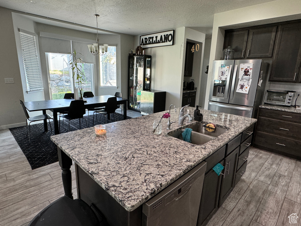 Kitchen featuring hanging light fixtures, a kitchen island with sink, light hardwood / wood-style flooring, sink, and stainless steel appliances