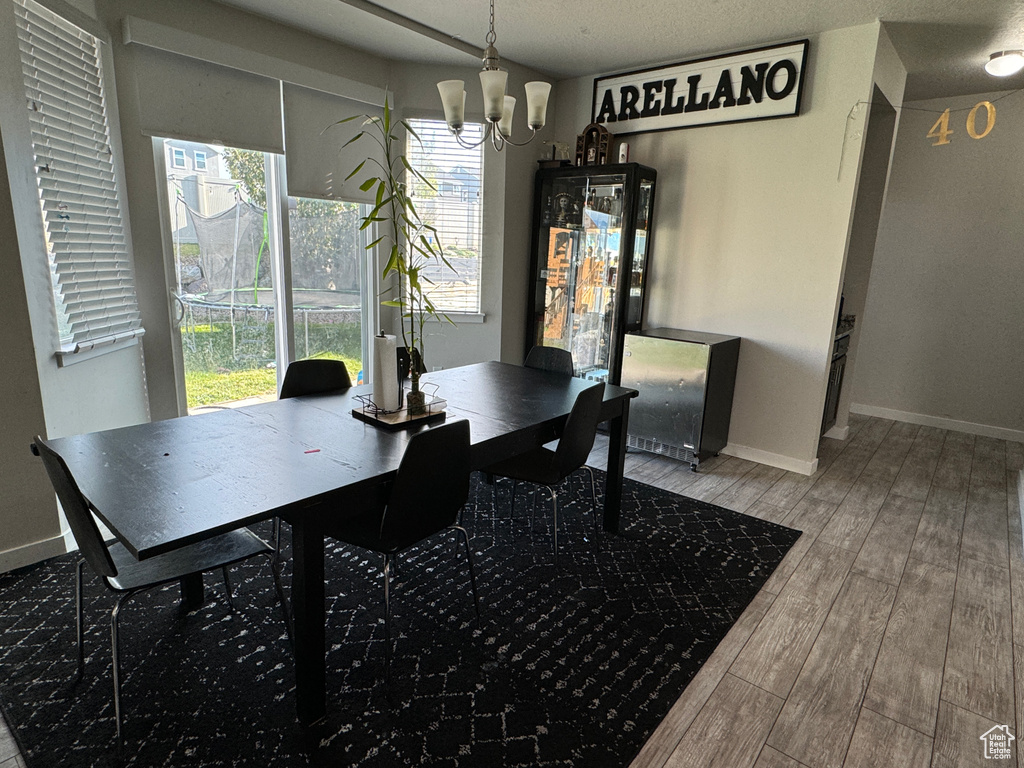 Dining space featuring hardwood / wood-style flooring, a textured ceiling, and an inviting chandelier