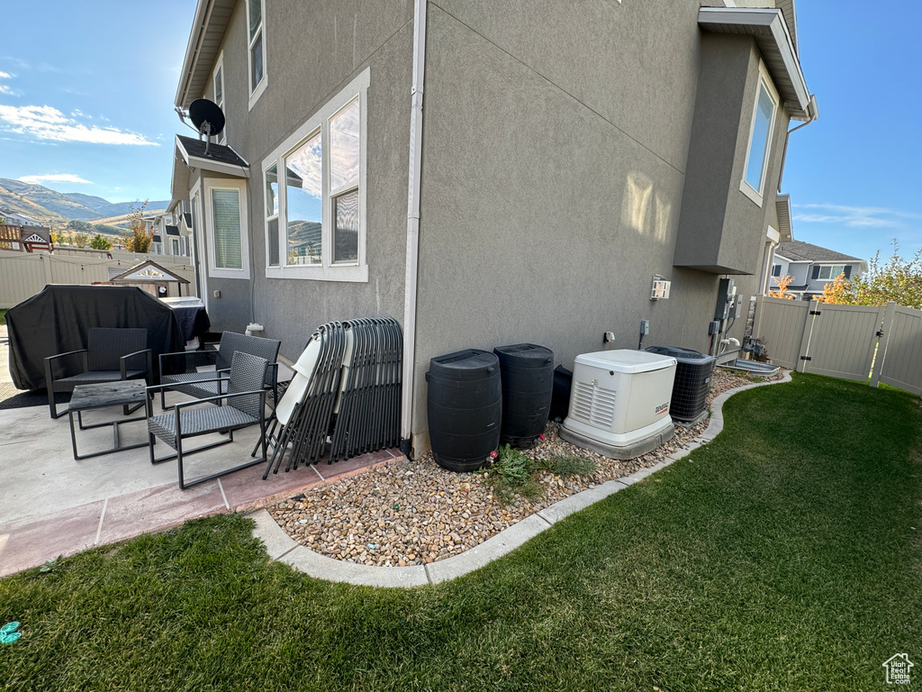 Rear view of house with a yard, a mountain view, a patio, and central AC unit