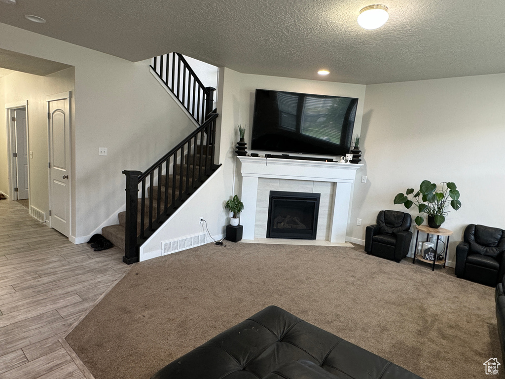 Living room featuring hardwood / wood-style floors, a tiled fireplace, and a textured ceiling