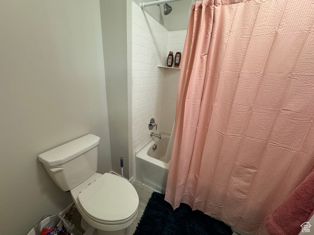 Bathroom with toilet and shower / bath combo with shower curtain