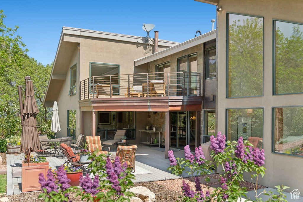 Rear view of house featuring a balcony, outdoor dining area, stucco siding, and a patio area