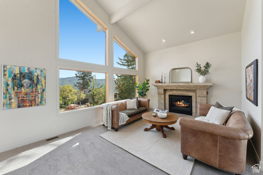 Carpeted living area with a glass covered fireplace, high vaulted ceiling, and beamed ceiling