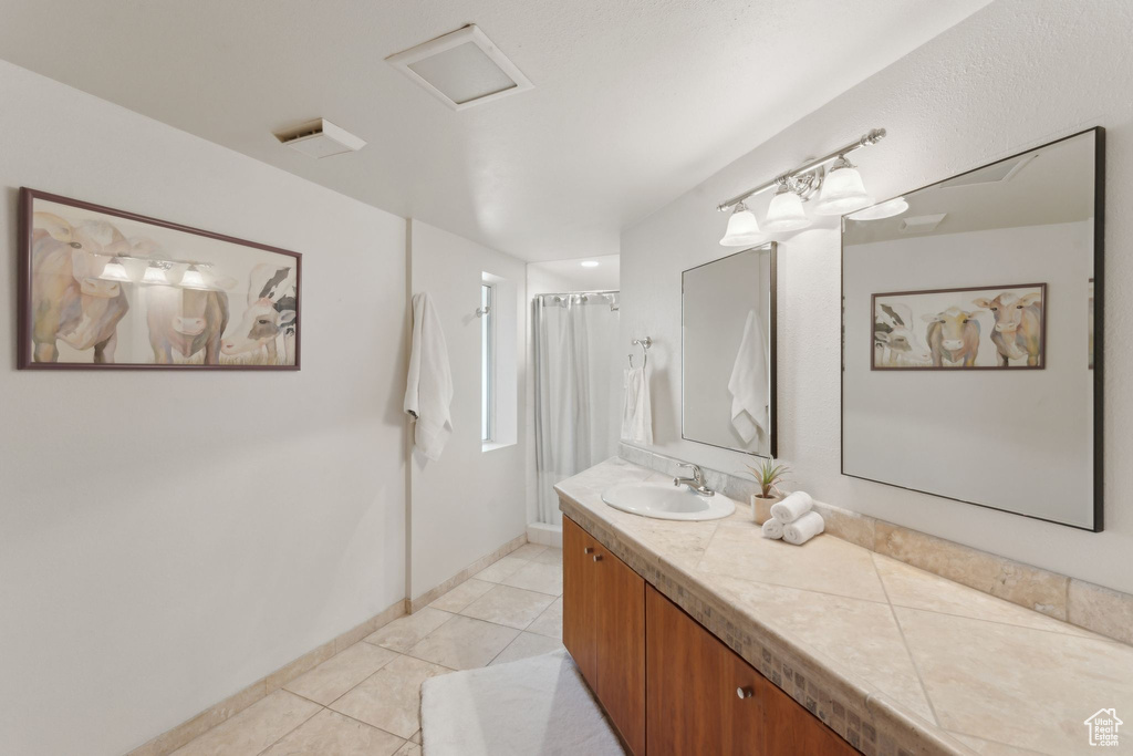 Full bath with tile patterned floors, vanity, a shower with curtain, and baseboards