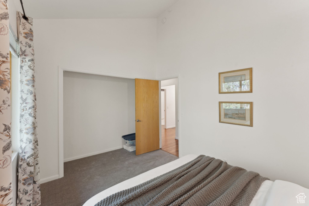 Bedroom featuring carpet, baseboards, and a towering ceiling