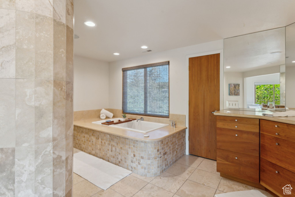 Bathroom featuring vanity, a bath, tile patterned floors, and recessed lighting
