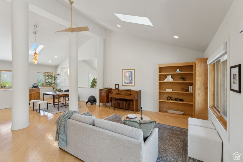 Living area with a skylight, high vaulted ceiling, light wood-style floors, recessed lighting, and baseboards