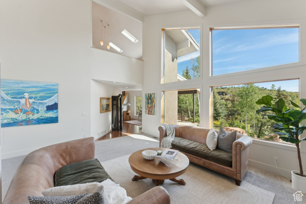 Living area featuring a high ceiling, baseboards, and beam ceiling