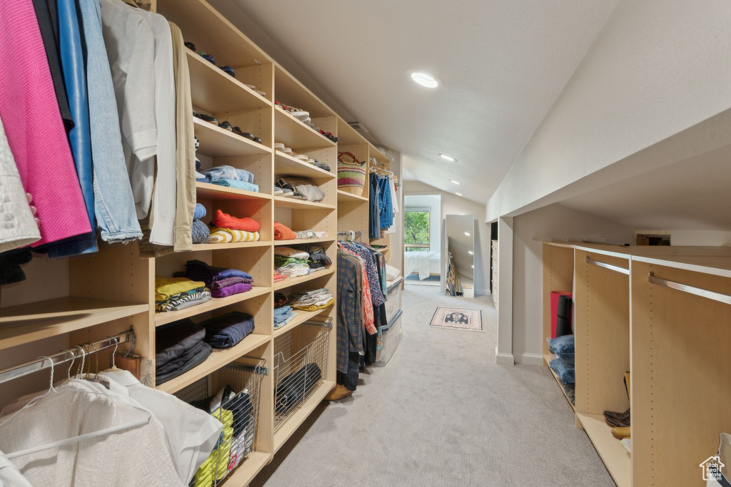 Walk in closet with lofted ceiling and carpet flooring