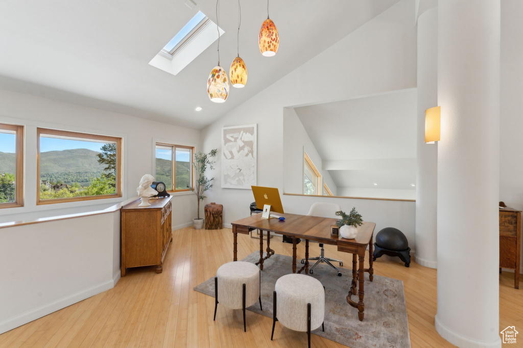 Office area featuring a skylight, light wood-style flooring, high vaulted ceiling, and baseboards