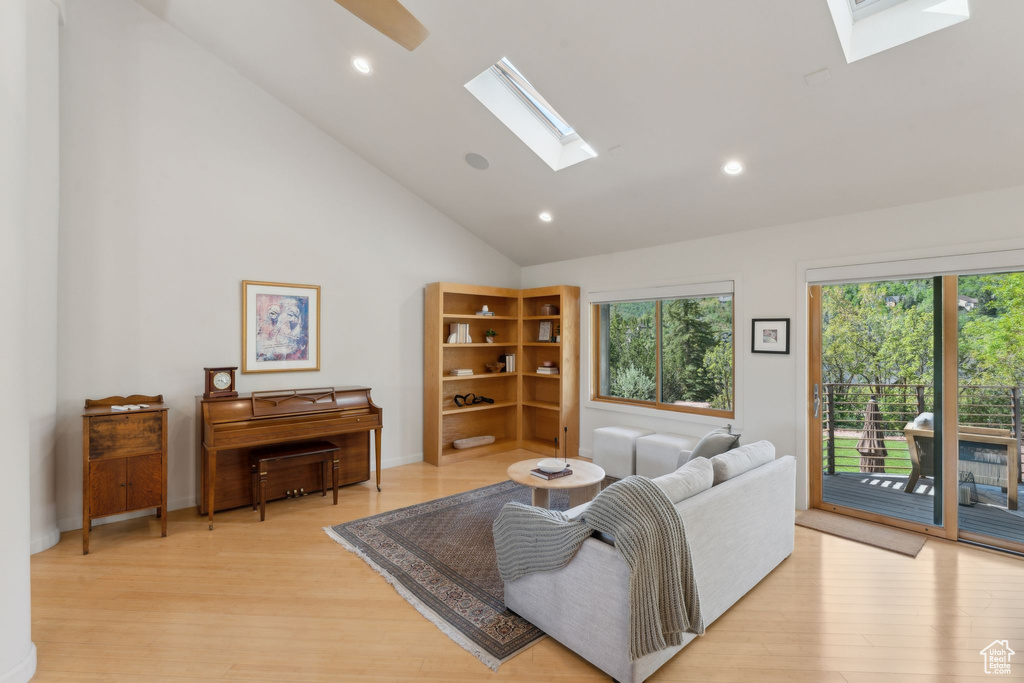 Living room featuring a skylight, light wood finished floors, recessed lighting, and high vaulted ceiling