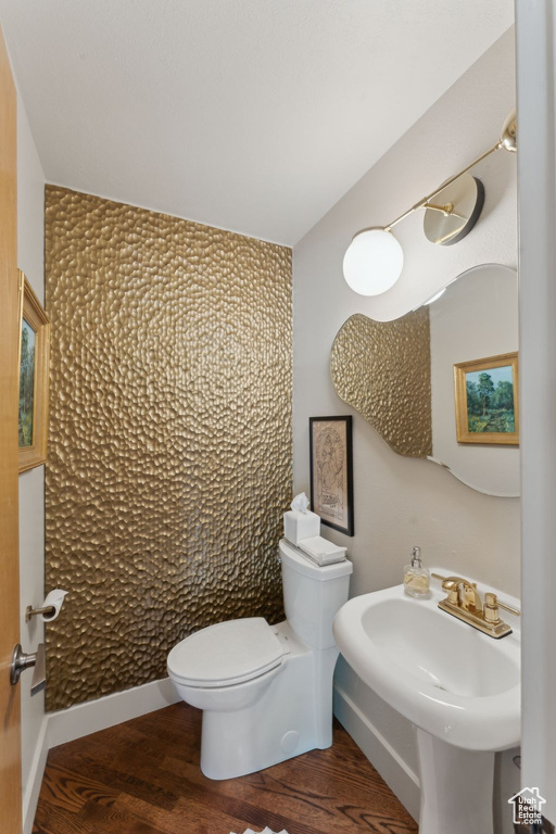 Bathroom featuring toilet, wood finished floors, and a sink