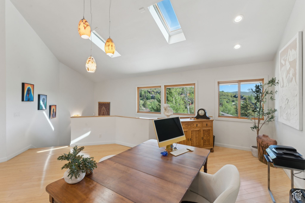 Office area with light wood finished floors, lofted ceiling, a skylight, baseboards, and recessed lighting