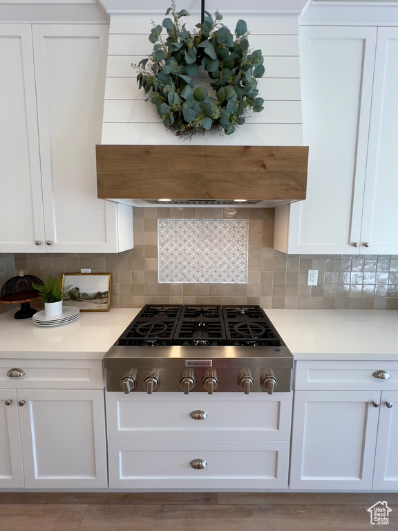 Kitchen with stainless steel gas stovetop, white cabinets, and light countertops