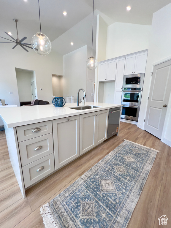 Kitchen with a sink, stainless steel appliances, high vaulted ceiling, a kitchen island with sink, and open floor plan