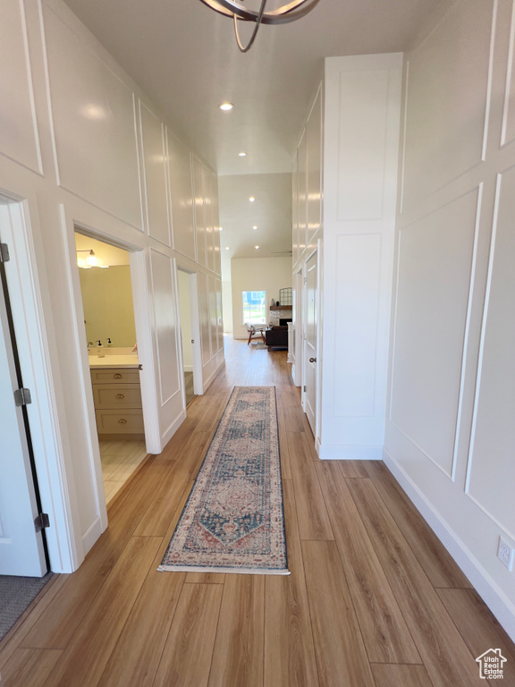 Corridor featuring light wood-style flooring, recessed lighting, and a decorative wall