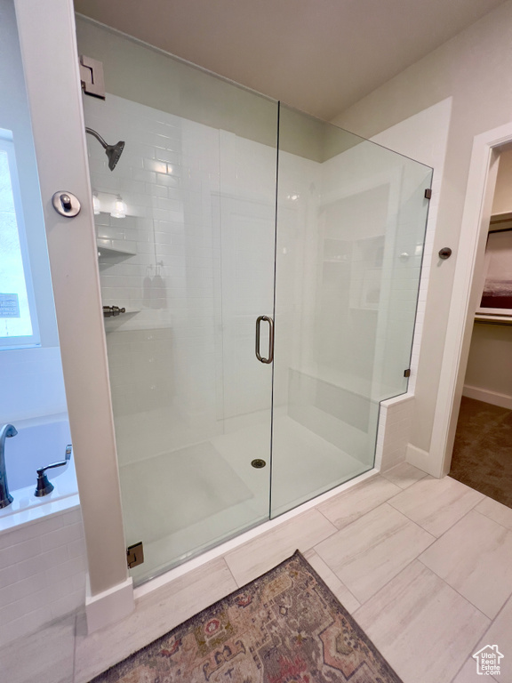 Full bathroom with a stall shower, a bath, and a spacious closet