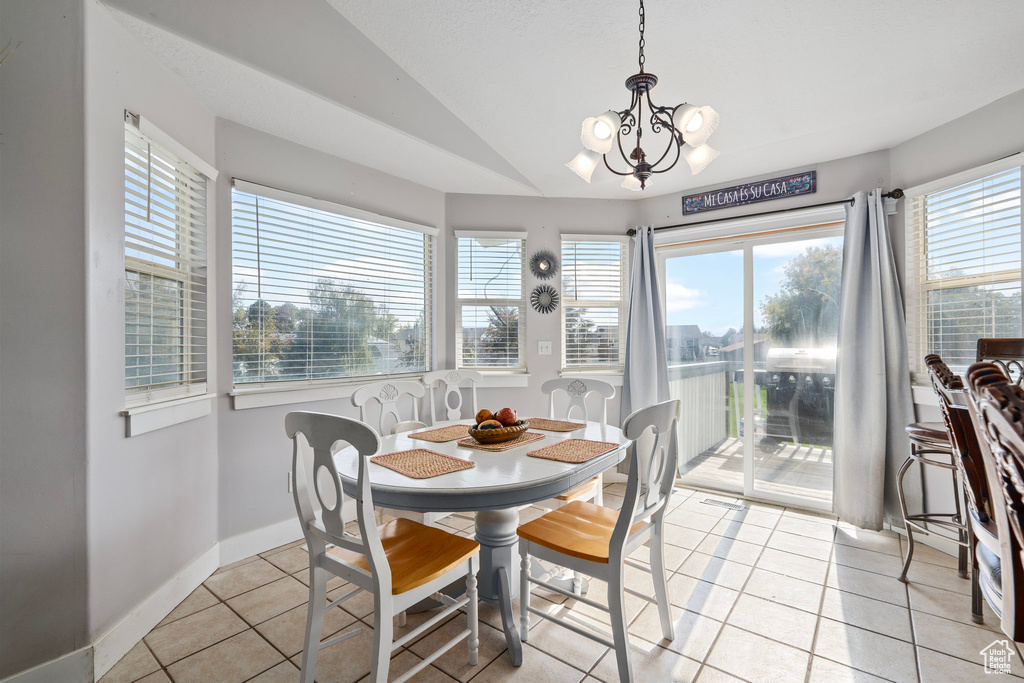 Tiled dining area with a notable chandelier and vaulted ceiling