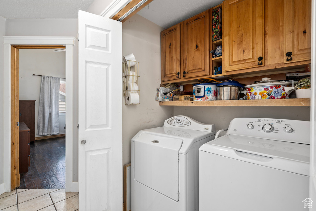 Laundry area featuring separate washer and dryer, light hardwood / wood-style floors, and cabinets