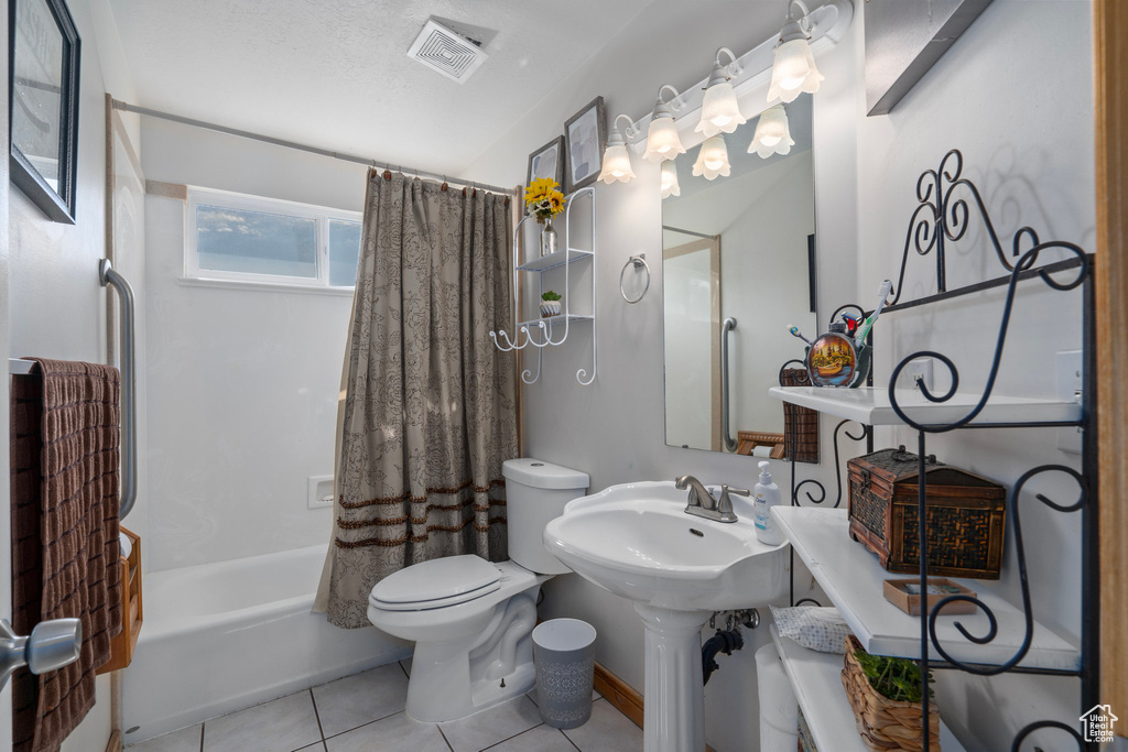 Bathroom featuring toilet, a textured ceiling, shower / tub combo with curtain, and tile patterned floors