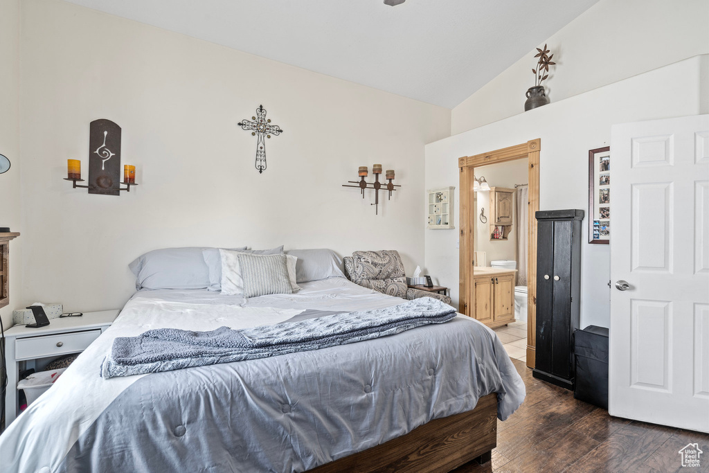 Bedroom featuring lofted ceiling, dark hardwood / wood-style floors, and ensuite bath