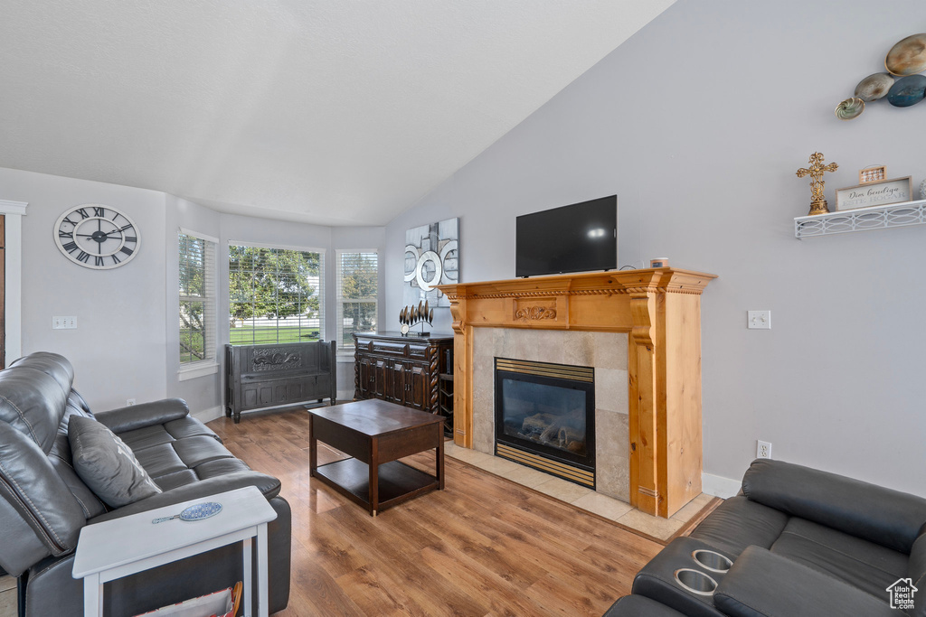 Living room featuring hardwood / wood-style floors, high vaulted ceiling, and a tile fireplace