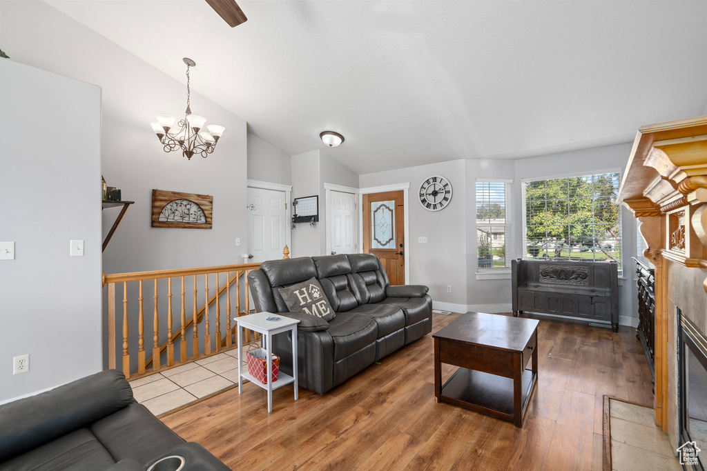 Living room with a notable chandelier, hardwood / wood-style flooring, and lofted ceiling