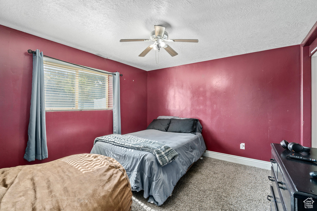 Carpeted bedroom with ceiling fan and a textured ceiling