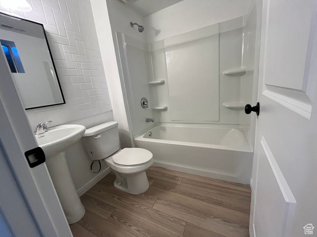 Bathroom featuring shower / bathing tub combination, hardwood / wood-style flooring, and toilet