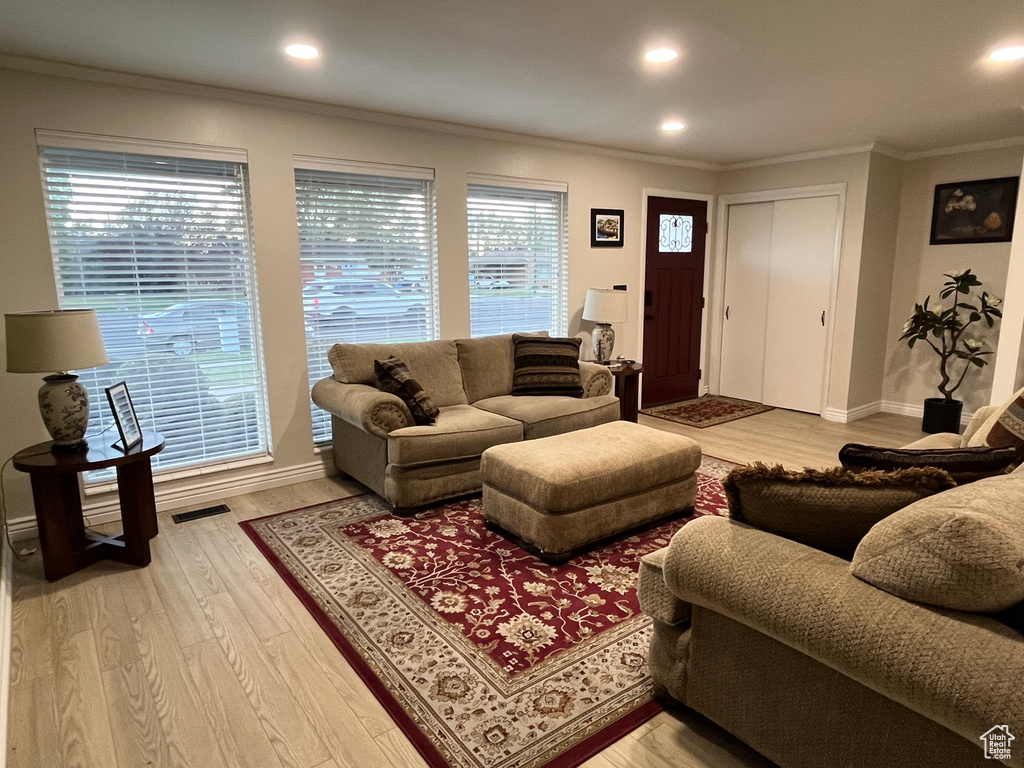 Living room with ornamental molding and hardwood / wood-style floors