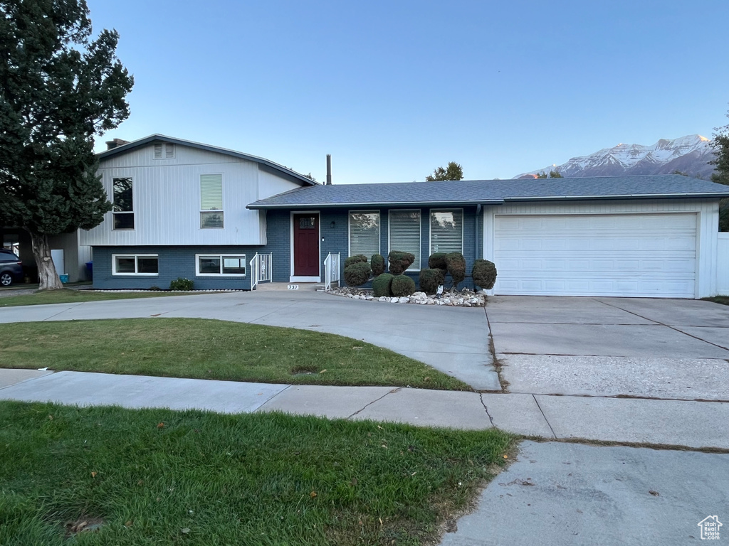 Tri-level home with a front yard, a garage, and a mountain view